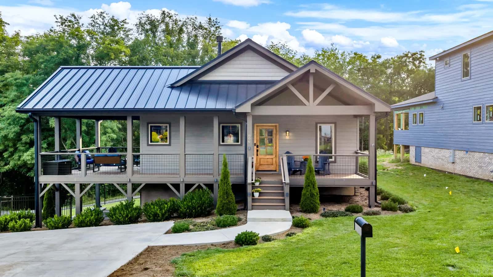 Completed custom home with a metal roof and covered porch on a landscaped lawn in West Jefferson, NC